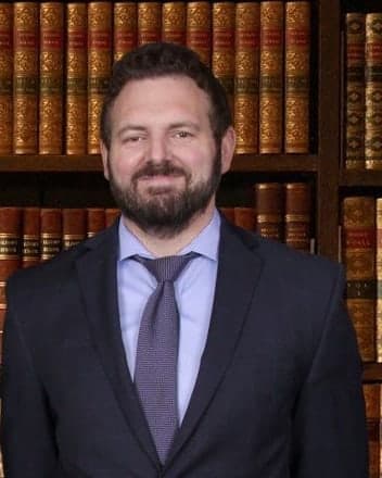 Conor P. O'Brien, partner, in a navy suit in front of a bookcase.
